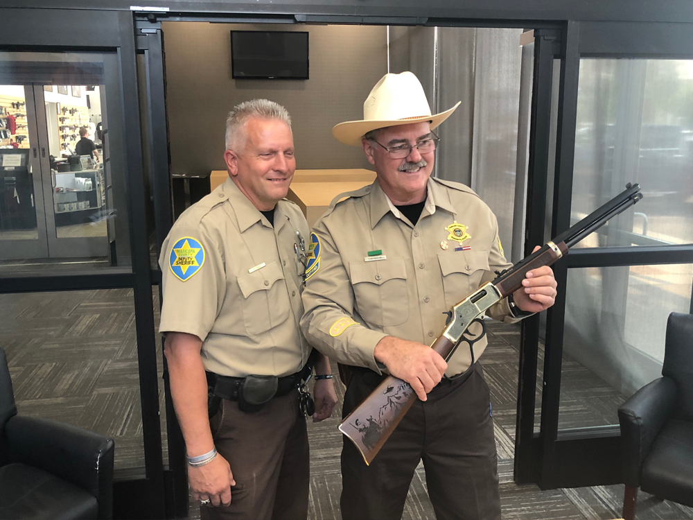 Two MCSO deputies holding the 150th anniversary commemorative rifle