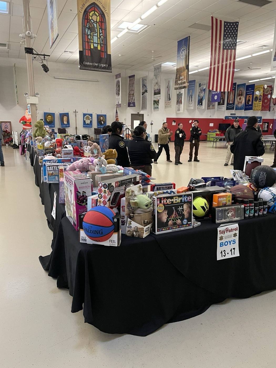 Deputies beside tables of donated toys under the flag